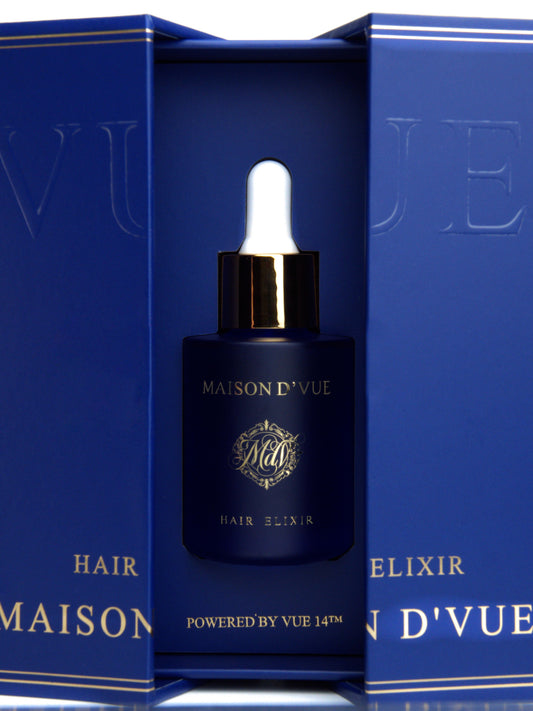 Maison D'Vue Hair Elixir hair serum bottle in a deep blue glass bottle with a gold collar and white dropper, presented inside an open matching blue gift box with gold lettering.