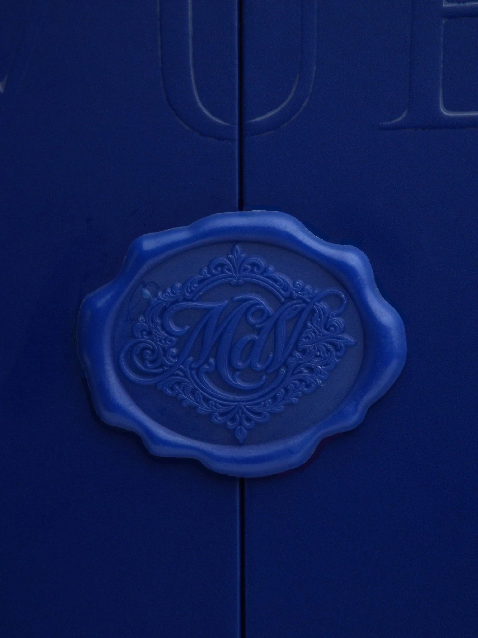 The MAISON D'VUE wax seal — a navy cobalt impression bearing the maison's monogram, signing each composition led by founder Masiela Lusha